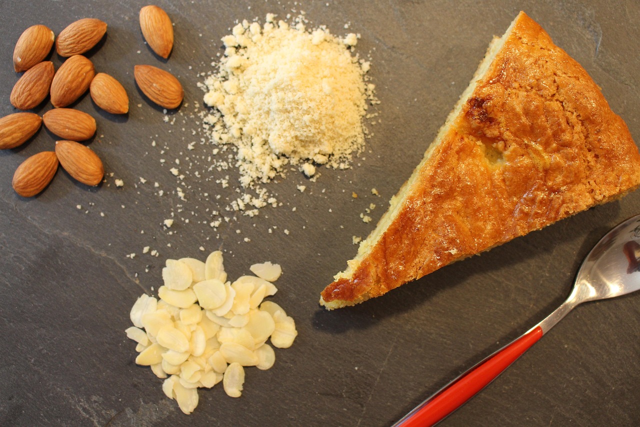 Part de galette des rois avec couronne dorée et fève sur une table en bois.